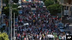 Palestinians living in Lebanon hold placards and Palestinian flags during a march in support of Palestinians, in Beirut, Lebanon, May. 18, 2021.