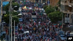 Palestinians living in Lebanon hold placards and Palestinian flags during a march in support of Palestinians, in Beirut, Lebanon, May. 18, 2021.