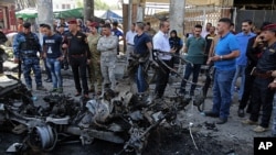 Pasukan keamanan Irak dan warga sipil memeriksa lokasi ledakan bom di Baghdad, Irak, 30 Mei 2017. (AP Photo/Karim Kadim)