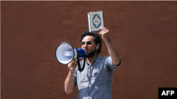 Salwan Momika melakukan aksi protes sambil membawa Al-Qur'an di luar sebuah masjid di Stockholm, Swedia, pada 28 Juni 2023. (Foto: AFP/Jonathan Nackstrand)