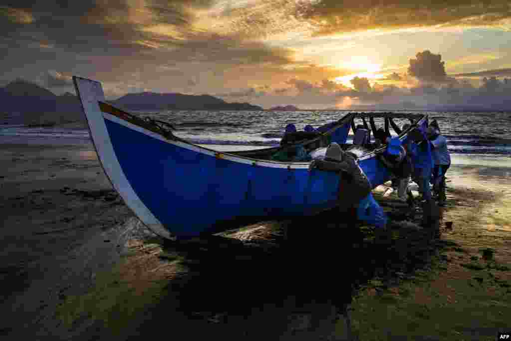 Fishermen push their boat onto the shore upon returning from the sea as the sun sets in Banda Aceh, Indonesia.