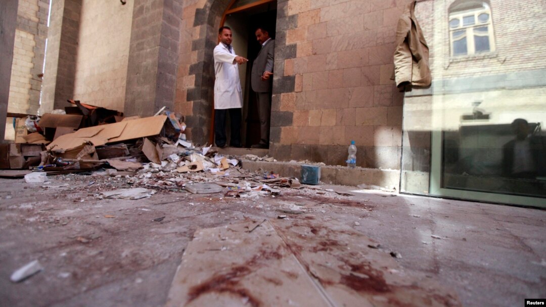 A doctor points at blood inside the hospital at the scene of the attack during a tour for journalists and survivors at the Defense Ministry in Sana'a Dec. 19, 2013.