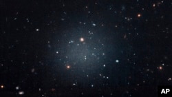 This image made with the Hubble Space Telescope shows the diffuse galaxy NGC 1052-DF2, lighter area in center, Nov. 16, 2017. Several other galaxies can be seen through it. The unusual galaxy’s stars are speeding around with no apparent influence from dark matter, according to a study published March 28, 2018, in the journal Nature.