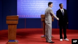 Stand-ins for Republican presidential candidate, former Massachusetts Gov. Mitt Romney, left, and President Barack Obama, shake hands during a rehearsal for a debate at the University of Denver, Oct. 2, 2012, in Denver.