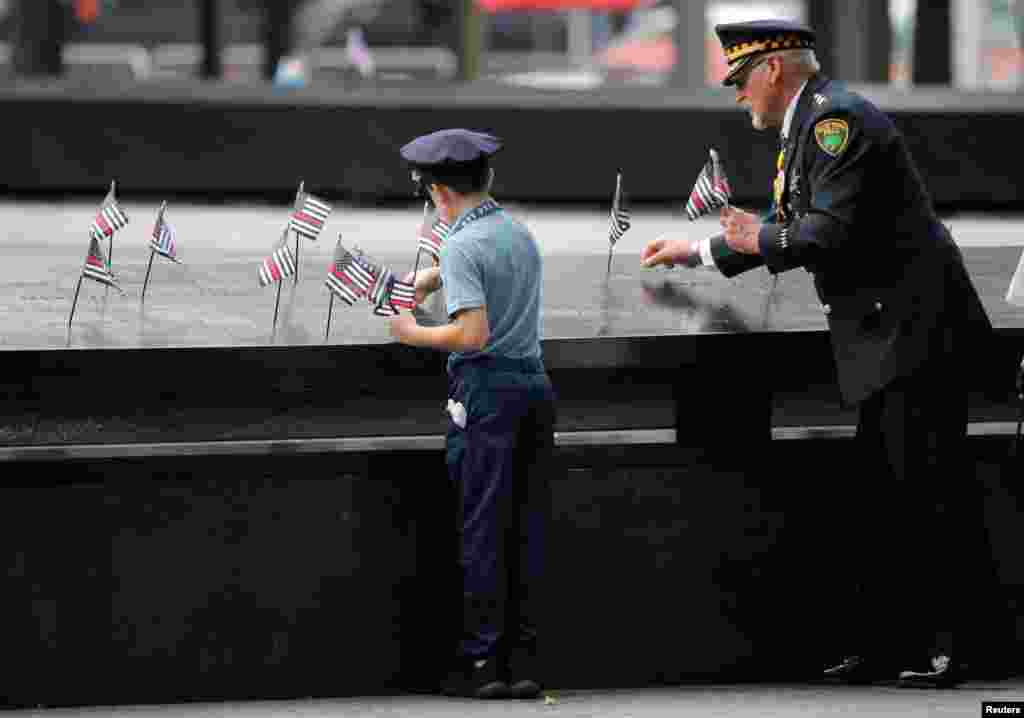  People place flags into the egraved names of 911 victims at the edge of the south reflecting pool during ceremonies commemorating the 18th anniversary of the 9/11 at the 9/11 Memorial in lower Manhattan in New York, Sept. 11, 2019.