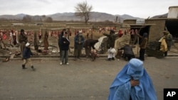 A burqa-clad woman crosses the street as butchers man their meat stalls outside Kabul, Afghanistan, 30 Dec 2010