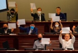 Pro-democracy lawmakers raise white papers to protest during a meeting to discuss the new national security law at the Legislative Council in Hong Kong, July 7, 2020.
