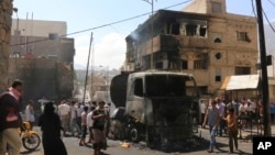 People gather around a truck carrying oil that was hit by crossfire between fighters loyal to the exiled President Abed Rabbo Mansour Hadi and Shi'ite rebels in Taiz city, Yemen, May 25, 2015. 