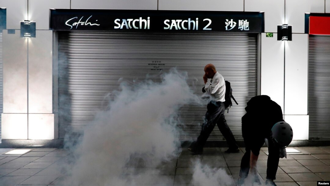 A man walks past an anti-extradition bill protester as he tries to pick up a tear gas canister at Tsim Sha Tsui after a demonstration in Hong Kong, Aug. 10, 2019.