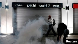 A man walks past an anti-extradition bill protester as he tries to pick up a tear gas canister at Tsim Sha Tsui after a demonstration in Hong Kong, Aug. 10, 2019.