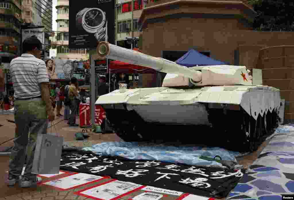 Seorang pembeli di Hong Kong berdiri di depan sebuah tank tiruan hasil karya para mahasiswa untuk mengenang peristiwa di Lapangan Tiananamen (3/6).