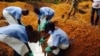 Volunteers lower a corpse into a grave in Kailahun, Sierra Leone that was prepared with safe burial practices to ensure it does not pose a health risk to others in order to stop the chain of person-to-person transmission of Ebola, August 2, 2014.