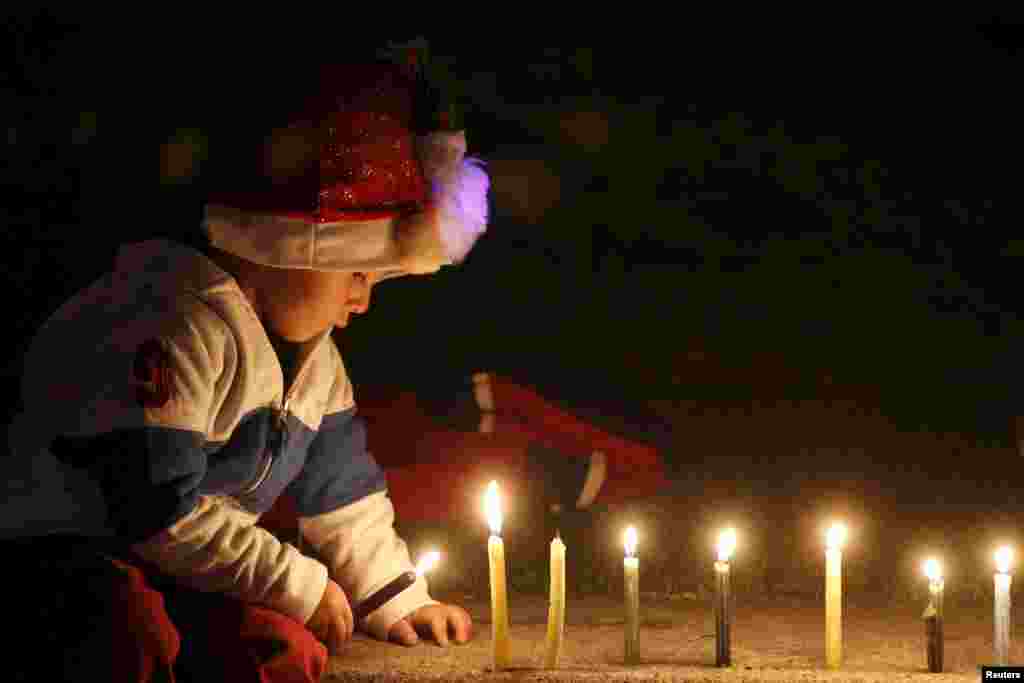 A child lights candles at the Park Simon Bolivar in Bogota, Dec. 7, 2015. Colombians light up candles on Dec. 7 every year to mark the start of Christmas festivities.