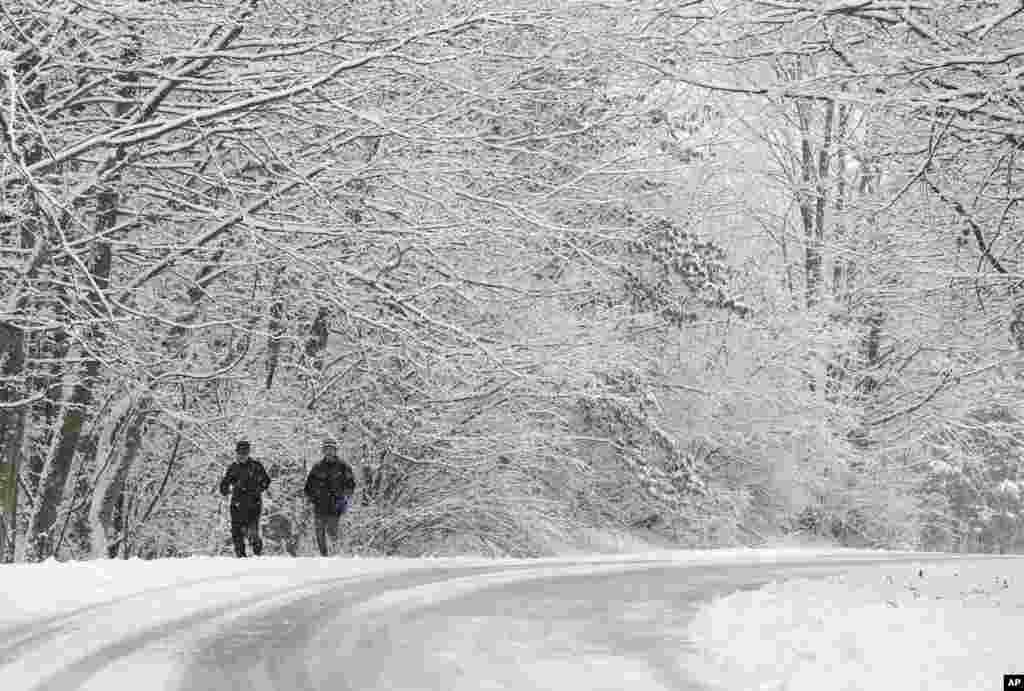Ken Perry and Stan Ly go for a run in Eagle Creek Park as snow falls in Indianapolis, Indiana, USA.
