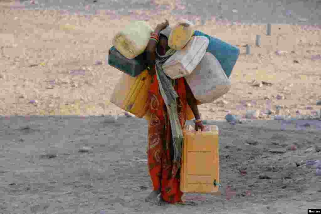 A girl carries cans to fill with drinking water at a camp for displaced people from the Red Sea port city of Hodeidah near Aden, Yemen.