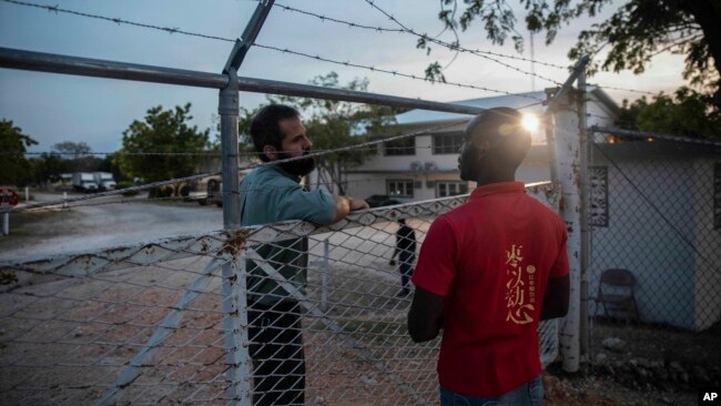 A manager at the Christian Aid Ministries headquarters, left, speaks with a worker at the door of the center in Titanyen, north of Port-au-Prince, Haiti, Sunday, Nov. 21, 2021. (AP Photo/Odelyn Joseph)