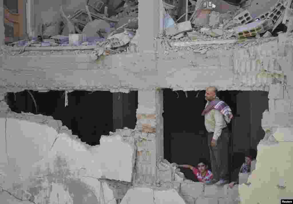 A man and boys inspect a site hit by what activists said was shelling by forces loyal to Syria's President Bashar al-Assad, Duma, Damascus, Sept. 4, 2013.