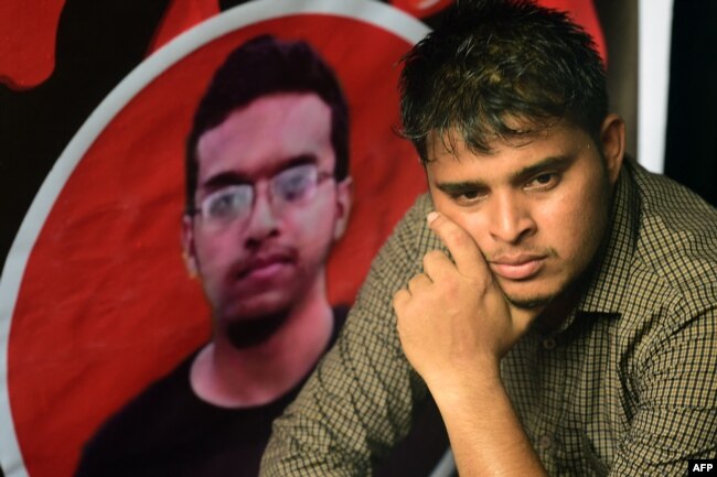 Seorang mahasiswa Bangladesh duduk di samping potret Abrar Fahad, mahasiswa yang tewas dianiaya di asrama kampusnya, dalam aksi protes di Dhaka, 7 Oktober 2019,