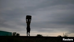 Storm clouds loom as a child carries water from a communal borehole near the capital Lilongwe, Malawi, Feb. 2, 2016. Floods and an El Nino-triggered drought have hit the staple maize crop exposing the fragility of Malawi's progress.