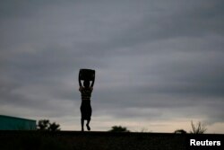 Storm clouds loom as a child carries water from a communal borehole near the capital Lilongwe, Malawi, Feb. 2, 2016. Floods and an El Nino-triggered drought have hit the staple maize crop in the country, a former food exporter.