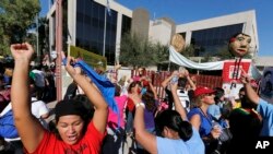 FILE - Protesters dance in front of the U.S. Immigrations and Customs Enforcement office with a goal of stopping future deportations, Oct. 14, 2013, in Phoenix. 