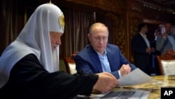 Russian President Vladimir Putin, with Russian Orthodox Patriarch Kirill, left, speak in the library of the Russian monastery St. Panteleimon at Karyes, on Mount Athos, Greece, May 28, 2016.