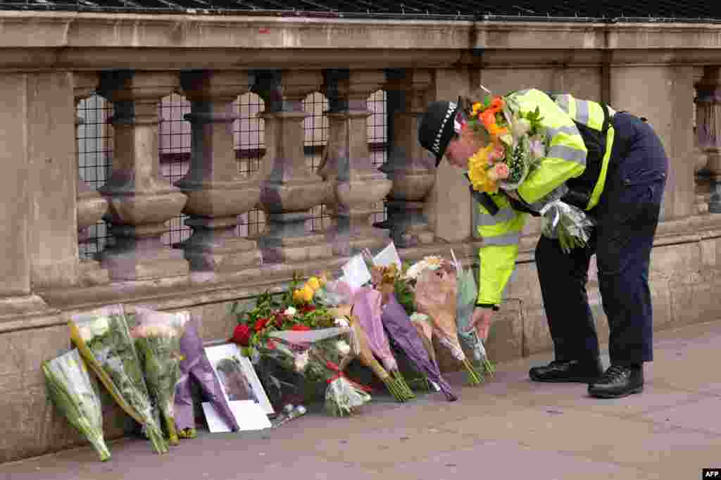 A police officer lays flowers on Whitehall around a photograph of police officer Keith Palmer who was killed in the March 22 terror attack in Westminster, near the Houses of the Parliament in central London on March 23, 2017. 