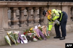 A police officer lays flowers on Whitehall around a photograph of police officer Keith Palmer who was killed in the March 22 terror attack in Westminster, near the Houses of the Parliament in central London on March 23, 2017.
