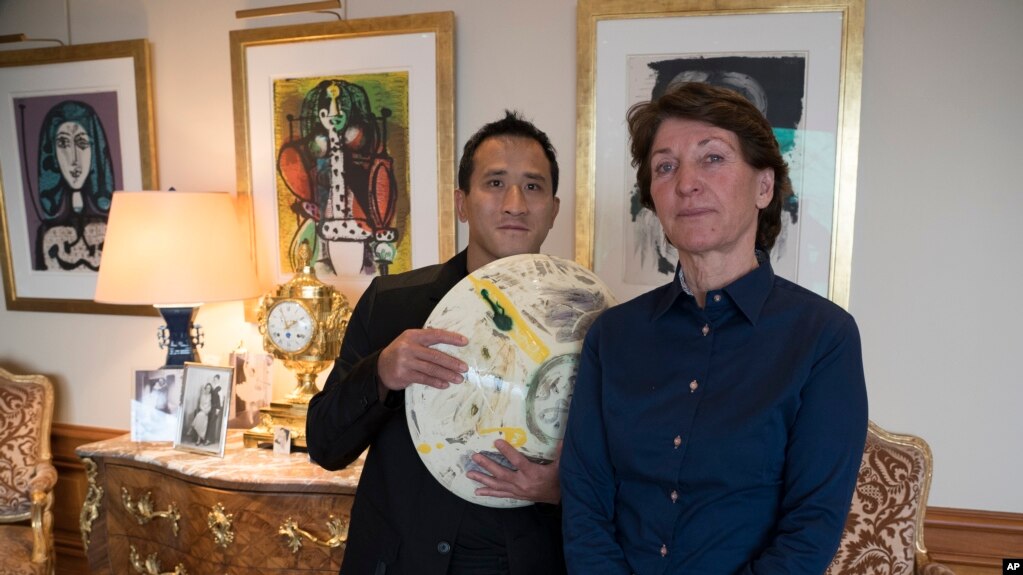 Marina Picasso, right, granddaughter of artist Pablo Picasso, and her son Florian Picasso pose with a ceramic art-work of Pablo Picasso in Cologny near in Geneva, Switzerland, Tuesday, Jan. 25, 2022. (AP Photo/Boris Heger)