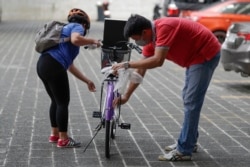 A winner, left, of a bicycle from the Benjamin Canlas Courage to be Kind Foundation prepares to ride. Photo taken in the financial district of Manila, Philippines, July 11, 2020.