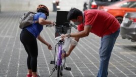 A winner, left, of a bicycle from the Benjamin Canlas Courage to be Kind Foundation prepares to ride. Photo taken in the financial district of Manila, Philippines, July 11, 2020.