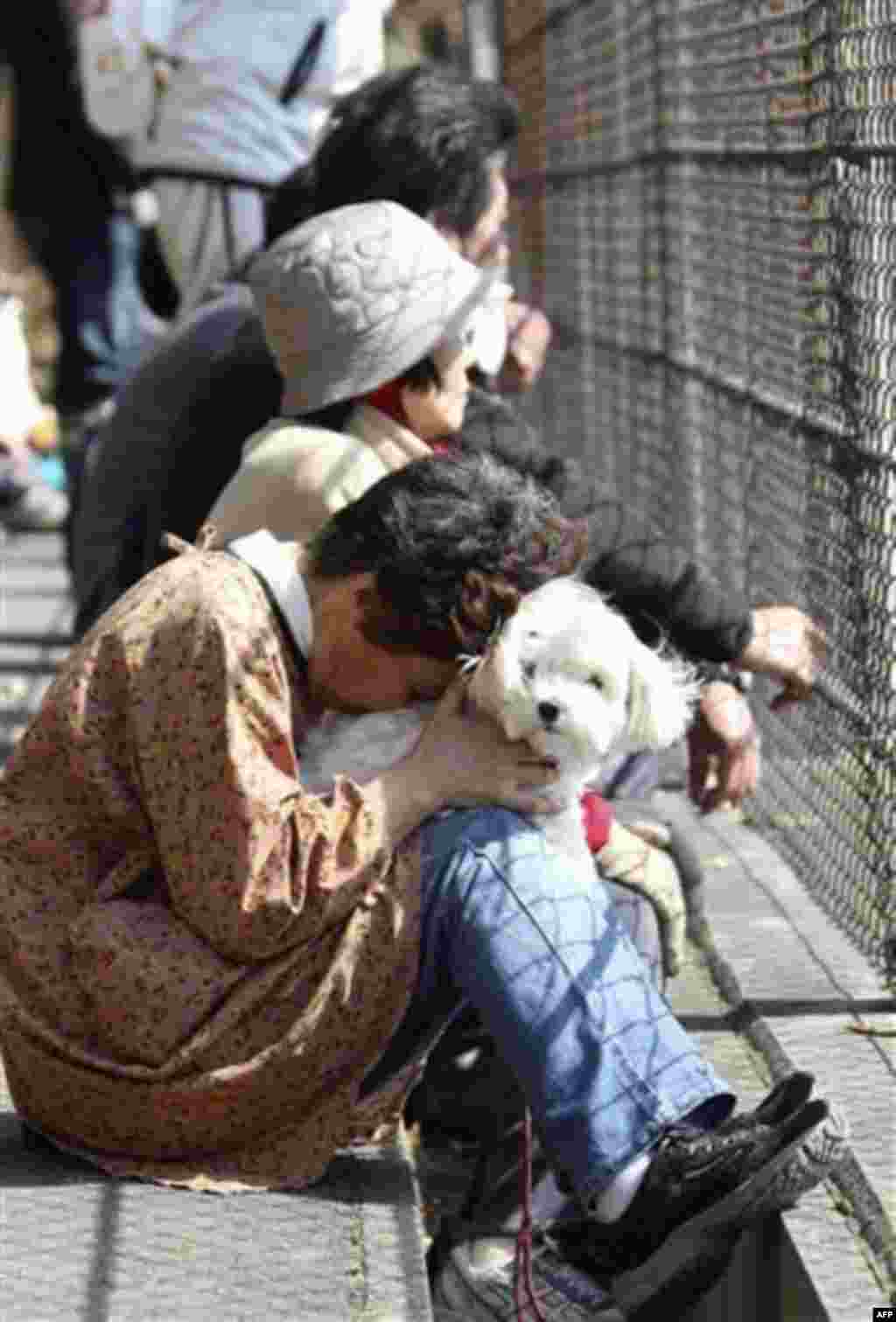 A woman holding her dog reacts after evacuating following a tsunami warning in Kamaishi, Iwate Prefecture, northern Japan, Monday, March 14, 2011, three days after a powerful earthquake-triggered tsunami hit the country's east coast. (AP Photo/The Yomiuri
