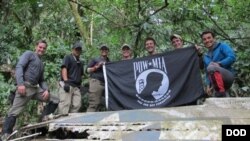 Members from Defense POW/MIA Accounting Agency (DPAA), hold the POW/MIA flag above a piece of metallic debris during a DPAA investigation mission near Bhismaknagar Village, Arunachal Pradesh, India, Dec. 02, 2016. 