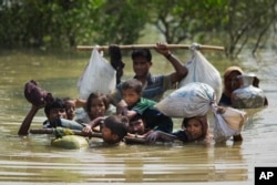 FILE - A Rohingya family reaches the Bangladesh border after crossing a creek of the Naf river on the border with Myanmmar, in Cox's Bazar's Teknaf area, Sept. 5, 2017.