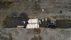 APTOPIX Workers wearing personal protective equipment bury bodies in a trench on Hart Island, Thursday, April 9, 2020, in the Bronx borough of New York