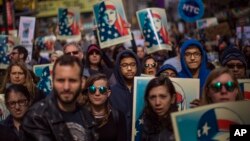 People carry posters during a rally in support of Muslim Americans and protest of President Donald Trump's immigration policies in Times Square, New York, Sunday, Feb. 19, 2017.