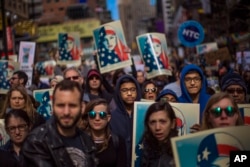 People carry posters during a rally in support of Muslim Americans and protest of President Donald Trump's immigration policies in Times Square, New York, Sunday, Feb. 19, 2017.