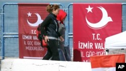 Un policier escorte un immigrant irrégulier dans un port turc, le 4 avril 2016.