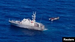 A Libyan coast guard vessel is pictured next to a migrant craft at sea, near Libya, June 5, 2019. A wooden boat carrying at least 22 African migrants was intercepted June 7 north of the Bouri offshore oil field, around 105 kilometers (65 miles) from Tripo