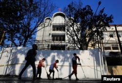 Beberapa orang mulai membersihkan bagian luar satu dari tiga gereja yang sehari sebelumnya diserang bom bunuh diri di Surabaya, 14 Mei 2018.