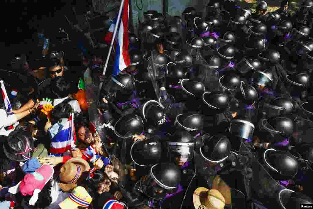 Anti-government protesters clash with riot police during a mass rally outside the house of Thai Prime Minister Yingluck Shinawatra in Bangkok in a bid to topple her before an uncertain February election the main opposition party will boycott.