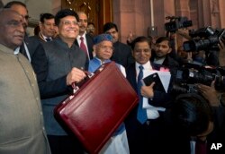 Interim Finance Minister Piyush Goyal, center, holds a briefcase containing federal budget documents with Junior Finance ministers Shiv Pratap Shukla, center right, and Pon Radhakrishnan, left, upon their arrival at the parliament house in New Delhi, India, Feb. 1, 2019.