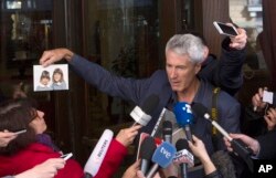 FILE - Anthony Foster, member of the Australian group of relatives and victims of priestly sex abuses, shows reporters a photo of his two daughters, who were both abused by the same priest and one of them later committed suicide, outside of the Quirinale hotel after their meeting with Australian cardinal George Pell, in Rome, March 3, 2016.