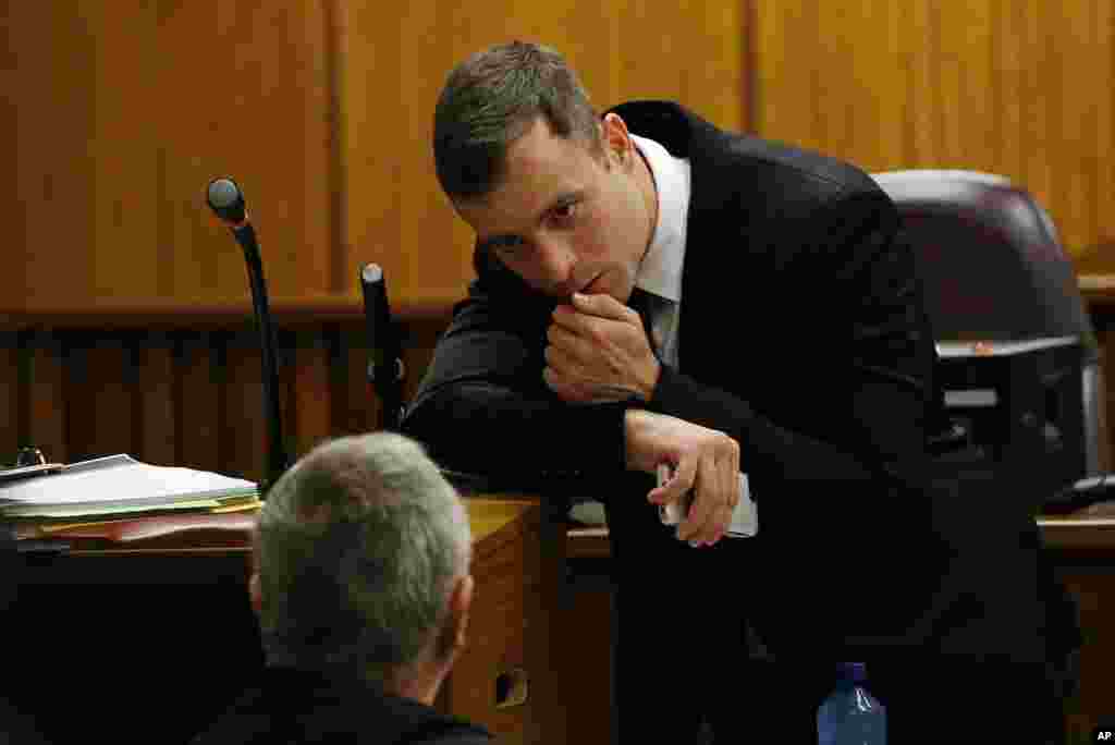 Oscar Pistorius speaks with his lawyer, Barry Roux, during the fourth day of sentencing proceedings in Pretoria, Oct. 16, 2014.