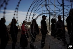 Migrantes hacen fila junto a una barrera de alambre de púas en Tijuana, México en uno de los principales cruces fronterizos para entrar a EE.UU. Noviembre 19 de 2018.