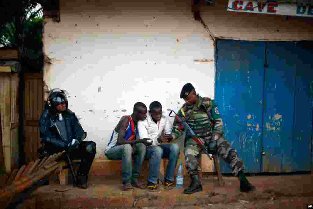 A uniformed FOMAC peacekeeper chats with local boys while another one dressed in full riot gear sits in the tense combatant neighborhood of Bangui, Central African Republic, Dec. 16, 2013. 