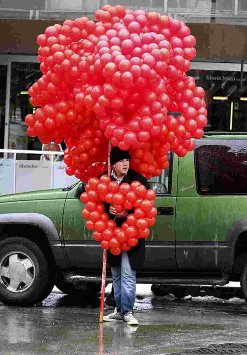 Seorang pria menjual rangkaian balon berbentuk hati di Ankara, Turki, 14 Februari (AP).