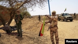 FILE - Fighter with Tuareg group MNLA brandishes separatist flag for region they call Azawad outside local regional assembly, Kidal, June 23, 2013.
