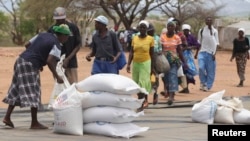 Zimbabweans collect food aid from a distribution point in Mutawatawa, about 220km northeast of the capital Harare, November 25, 2013. According to the World Food Programme (WFP), over 2 million FILE: Zimbabwean people are in need of food aid due to a poor harvest. Picture taken November 25, 2013. REUTERS/Philimon Bulawayo (ZIMBABWE - Tags: POLITICS SOCIETY) - RTX15TGB