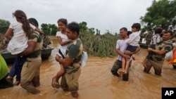 Binh lính Ấn Độ bế những em nhỏ được giải cứu khỏi những ngôi làng bị ngập lụt gần Thara ở quận Banaskantha, bang Gujarat, Ấn Độ, Wednesday, ngày 26 tháng 7, 2017.